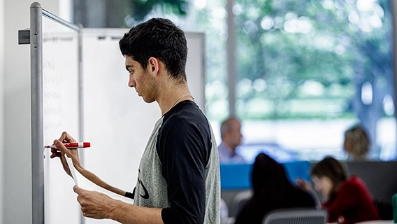 Student planning out a project at a whiteboard